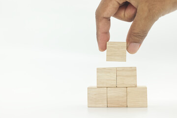 hand picking up wooden blank block cubes arranged in pyramid shape on white background