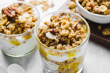 Granola and Yogurt Parfaits, Healthy Breakfast or Snack, Muesli with Nut Mix and Honey on Bright Concrete Background