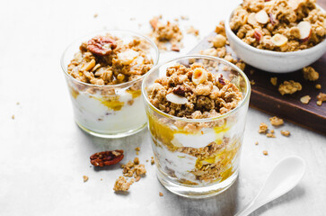 Granola and Yogurt Parfaits, Healthy Breakfast or Snack, Muesli with Nut Mix and Honey on Bright Concrete Background