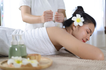 Woman Enjoying Herbal Massage. Relaxed Asian girl sleeping with eyes closed receiving traditional...