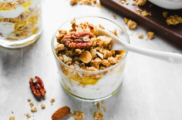 Granola and Yogurt Parfaits, Healthy Breakfast or Snack, Muesli with Nut Mix and Honey on Bright Concrete Background