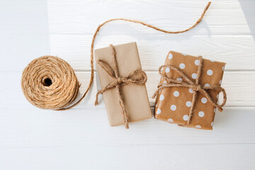 Eco gift wrapping. Brown gift boxes tied with a rope on white wooden background. Flat lay