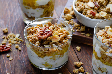 Granola and Yogurt Parfaits, Healthy Breakfast or Snack, Muesli with Nut Mix and Honey on Wooden Background