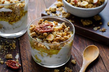 Granola and Yogurt Parfaits, Healthy Breakfast or Snack, Muesli with Nut Mix and Honey on Wooden Background