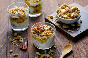 Granola and Yogurt Parfaits, Healthy Breakfast or Snack, Muesli with Nut Mix and Honey on Wooden Background