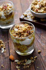 Granola and Yogurt Parfaits, Healthy Breakfast or Snack, Muesli with Nut Mix and Honey on Wooden Background