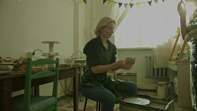 Girl teaching woman in her atmospheric craft workshop pottery studio