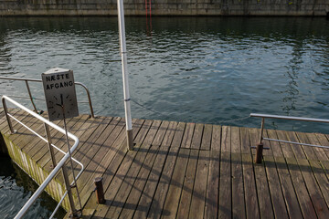 Outdoor top view over empty wooden deck pier and the sign with Danish words "naeste Afgang" means next departure.