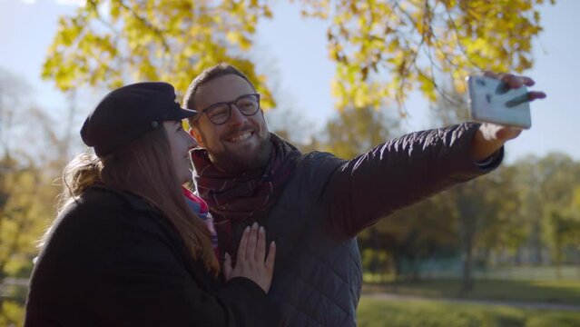 Happy couple in love making selfie on smartphone in park. Realtime