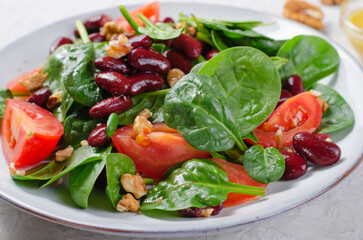 Red Bean Salad On Bright Background, Fresh Salad with Spinach, Cherry Tomatoes, Walnuts, Beans and Mustard Dressing