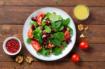 Red Bean Salad On Wooden Background, Fresh Salad with Spinach, Cherry Tomatoes, Walnuts, Beans and Mustard Dressing