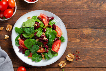 Red Bean Salad On Wooden Background, Fresh Salad with Spinach, Cherry Tomatoes, Walnuts, Beans and Mustard Dressing
