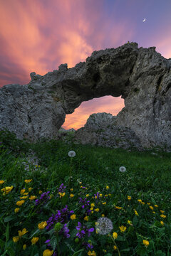 Double hole cave in mountainous terrain against sunset sky