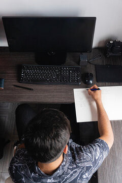 Man writing notes near computer