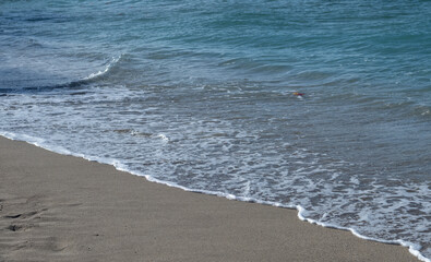 Blue Waves and White Foam on a Tan Sand Beach in Waikiki .