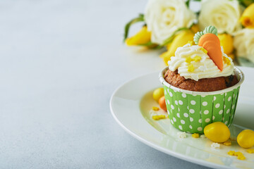 Carrot cake cupcakes for Easter. Carrot cupcakes with cream cheese frosting decorated with tiny marzipan carrots on white background. Happy Easter and spring holiday concept. Holydays homemade dessert