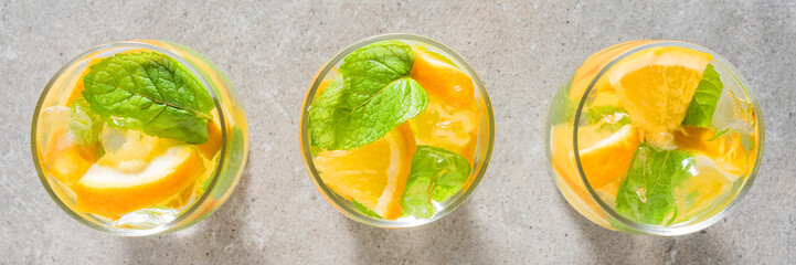 Refreshing orange drink with mint leaves and ice on gray stone table