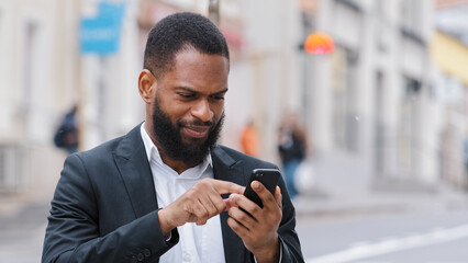 African American bearded man holding smartphone looking at mobile phone screen look for address with electronic online map app in city. Ethnic male professional businessman searching direction road