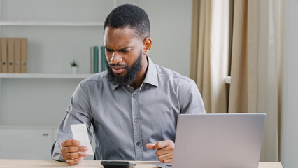 African American ethnic man bearded businessman manager business company CEO checking budget expenses check bill loan income accounting balance banking calculation with calculator counting credit