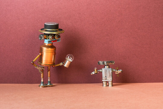 Toy robots with light bulbs. A large cyborg toy shows an electric light bulb to a small child robot standing next to it. Artificial intelligence and machine learning concept