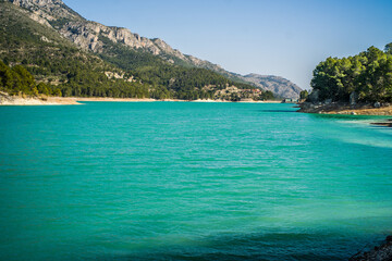 Naklejka premium Lake Guadalest, rocky mountains and hills covered with trees. Blue sky