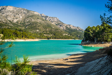 Fototapeta premium Lake Guadalest, rocky mountains and hills covered with trees. Blue sky