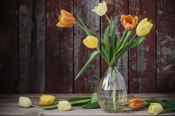tulips in glass vase on old wooden background