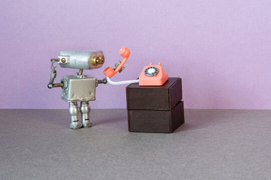 A miniature mechanical robot looks listens the phone handset.