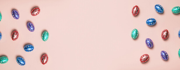 Easter hunt concept flat lay. Chocolate colorful eggs top view on colored background