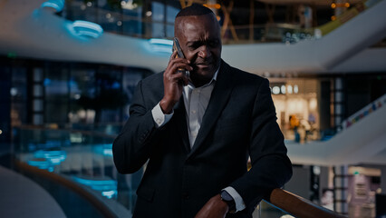Sad ethnic middle-aged man African American entrepreneur answer phone call talking smartphone talk...