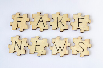 Wooden puzzles with Fake News on a white background. Misinformation, propaganda, clickbait, media literacy.