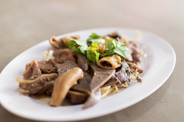 Boiled beef offal serve in a plate with dipping sauce.