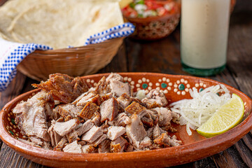 plato de carnitas de puerco en plato de barro, comida tipica mexicana