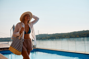 Young happy woman spends summer day at swimming pool.