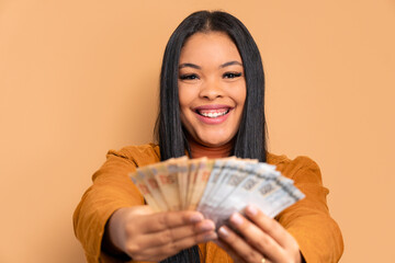 joyful afro brazilian woman celebrating successful business money in beige studio background. financial, credit, purchase, rich concept. 