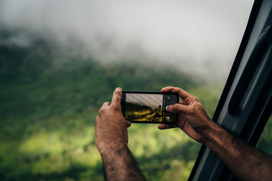 a person photographing a landscape using a mobile phone with an out of focus background