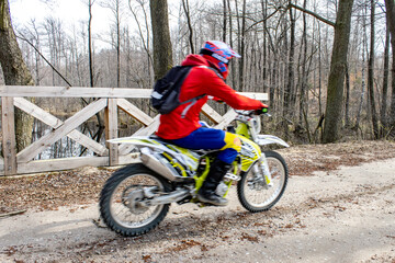 Motocross crossing the bridge in the forest in motion