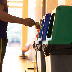 Young Asian men dump cans or plastic bottles in sorting bins for recycling, Garbage sorting and disposal, Environmental Love Project.
