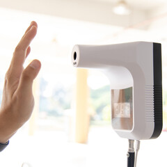 Young man used his palm to touch the sensor of the thermometer temperature using a non-contact infrared thermometer, Body temperature measurement device to prevent COVID-19 virus.