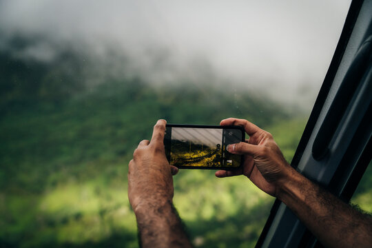 a person photographing a landscape using a mobile phone with an out of focus background