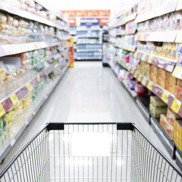 Shopping cart in supermarket, Abstract blurred photo in shopping malls, Cart in the market, wide variety of products are placed on the shelves for an orderly display.