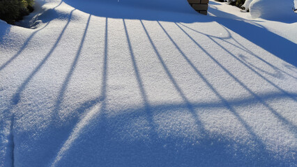 Abstract background with dark and light stripes of shadow on pure white snow on a sunny winter cold day