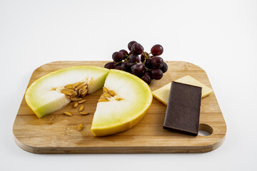 after dinner desset of fresh honeydew melon slice with grapes and white and dark chocolate isolated...