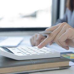 Financial or accounting professionals use a laptop to analyze the company's revenue-expenses graph to prepare for presentation to the chief executive and partner, businesswomen working in the room.