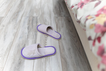 slippers near the bed on which the person sleeps.