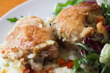 Oven baked chicken with rice and vegetables and fresh salad served on a plate. Tasty and healthy lunch