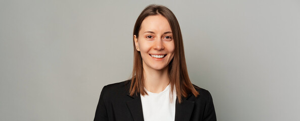 Banner size portrait shot over grey background of a young smiling woman.