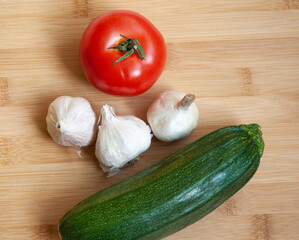 Fresh organic vegetables - potato, garlic, and zucchini on a cutting board.