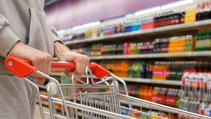 Close-up of a buyer's hands rolling a shopping trolley in the drinks department
