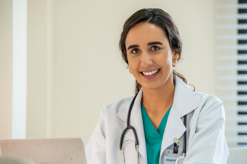 Woman female doctor portrait in white coat gown with stethoscope sit and smile to front. Medical...